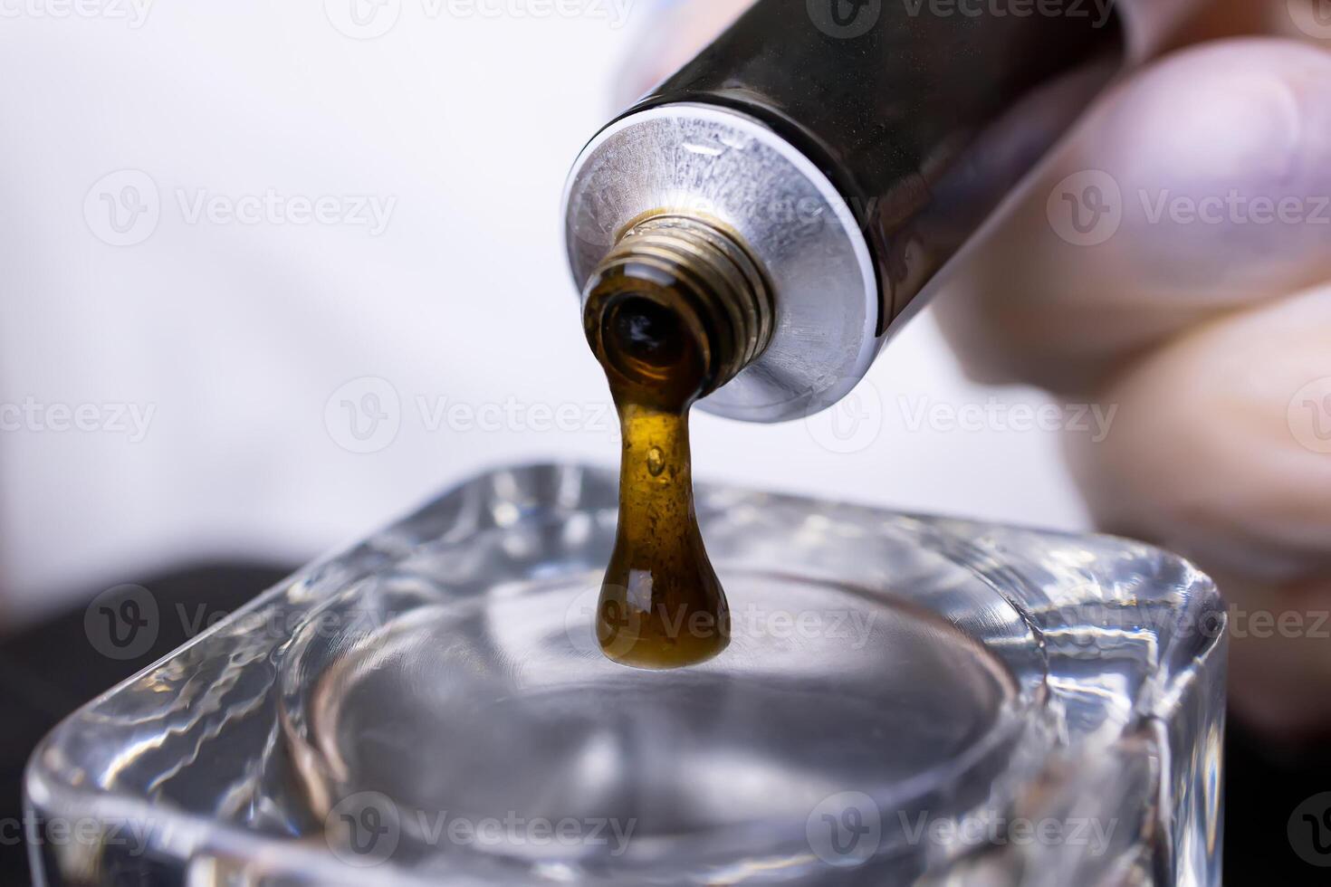 close-up of squeezing eyebrow paint from a tube into a glass cup photo