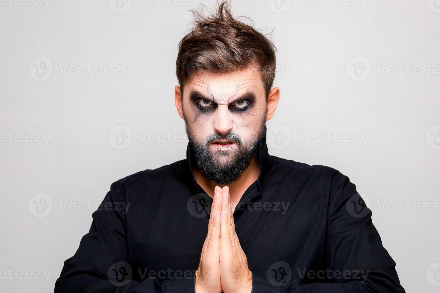 Scary undead-style makeup for Halloween on a bearded man who shows gestures photo