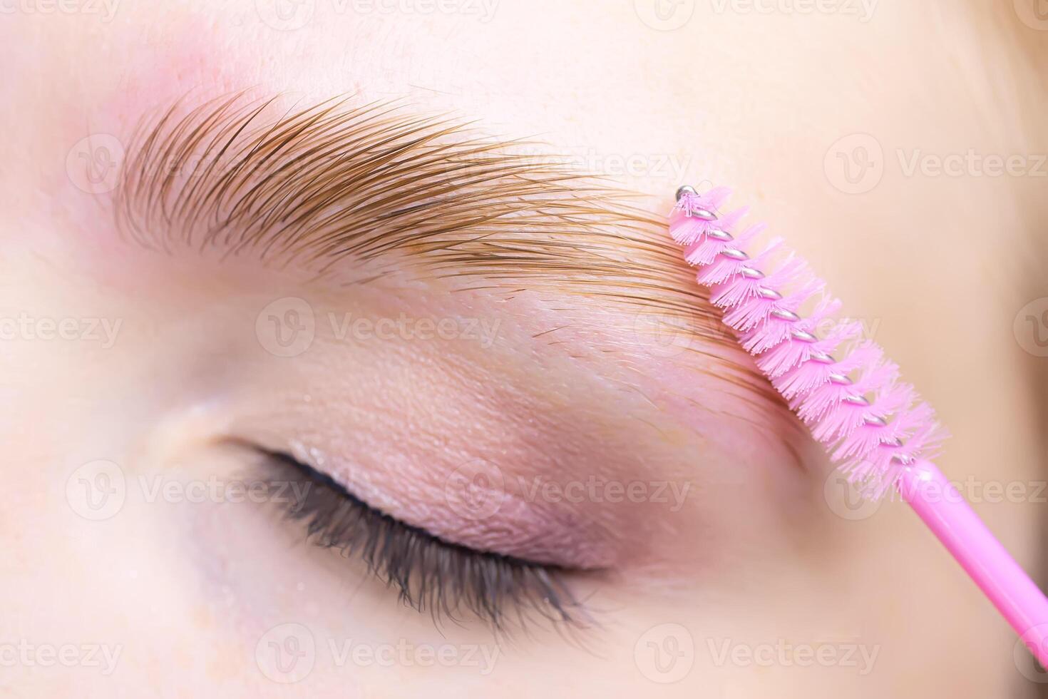 macro photography of the eye, the eyebrow of which is combined with a brush, the hairs are laid after the laminating composition photo