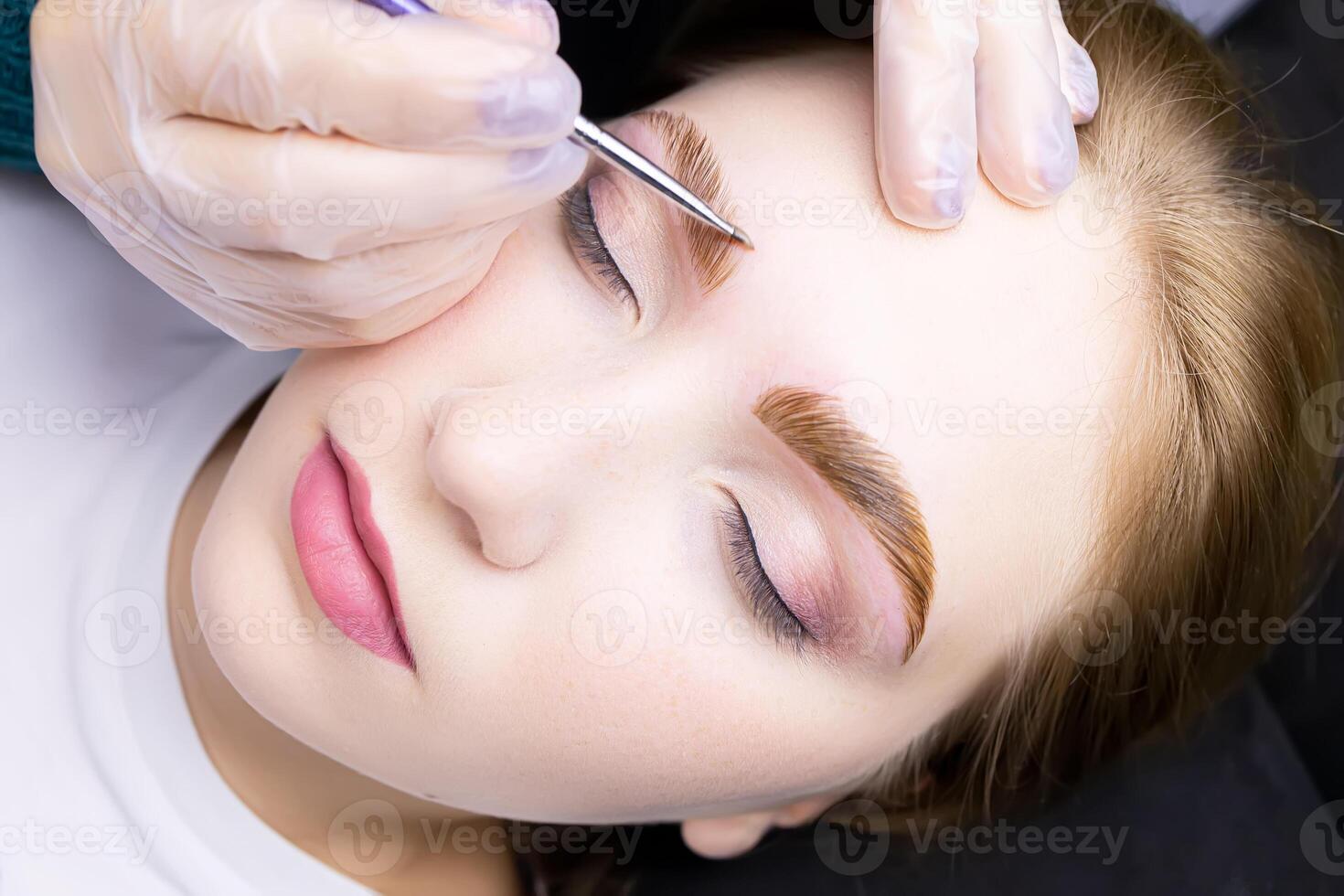 close-up of the model's face, the master applies a special hair dye to the eyebrows after the lamination procedure photo