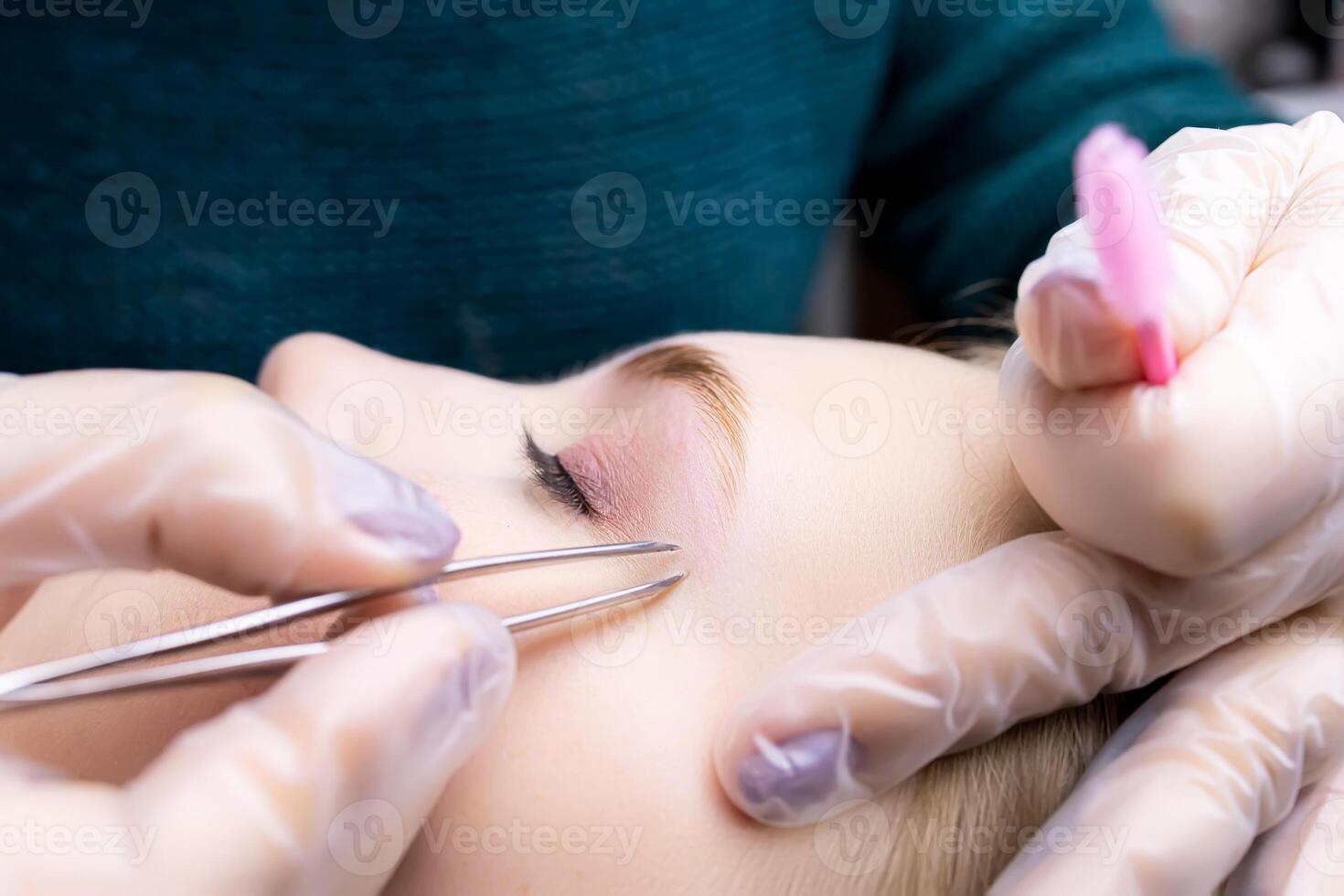 close-up of the eyebrows after the lamination procedure, the master tweezers to pluck the hairs photo