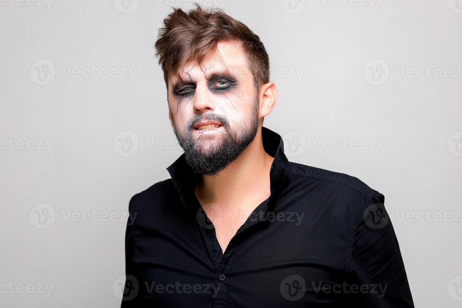 undead makeup for October 31 on a bearded man who shows teeth photo