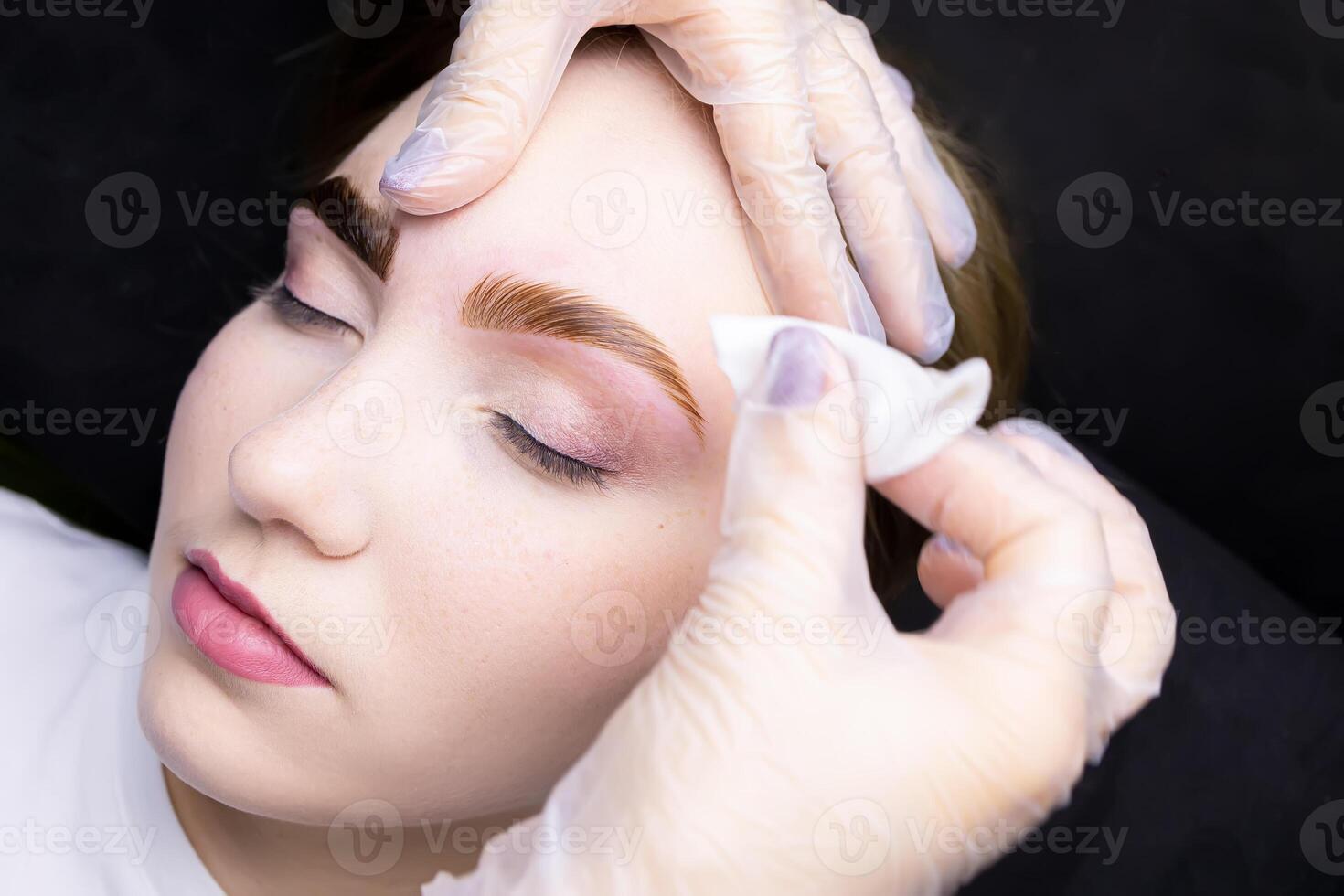 in the hands of the master is a cotton sponge with which he removes the remnants of paint from painted eyebrows photo