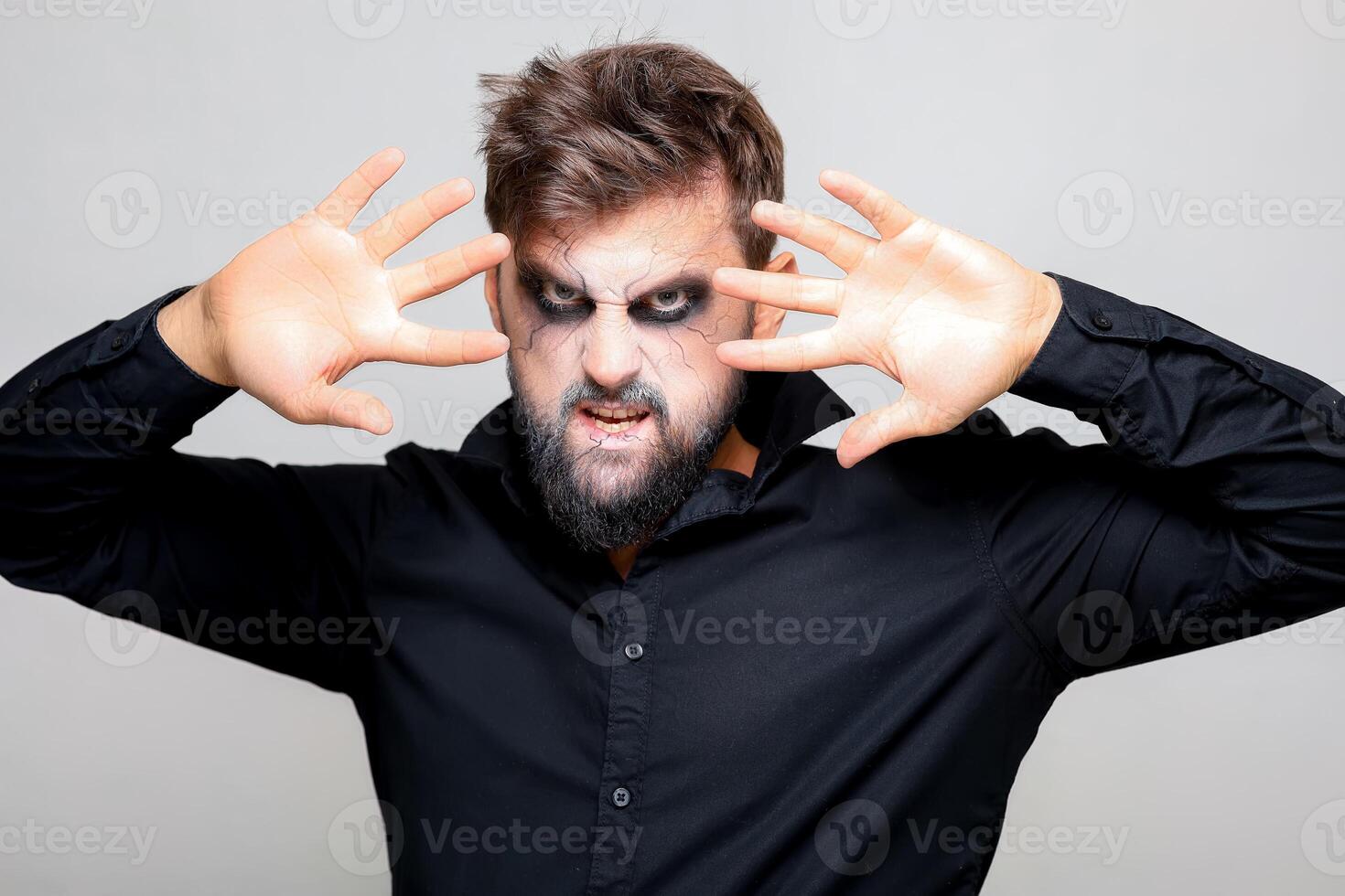 halloween makeup on a bearded man who gestures at the camera photo