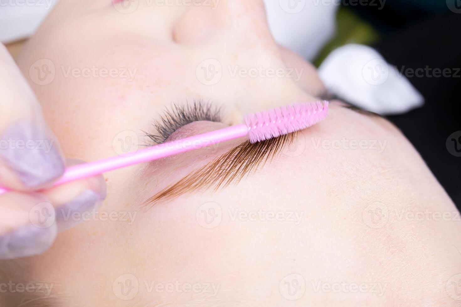 macro photography of combing eyebrow hairs with a brush after coloring and lamination with compounds photo