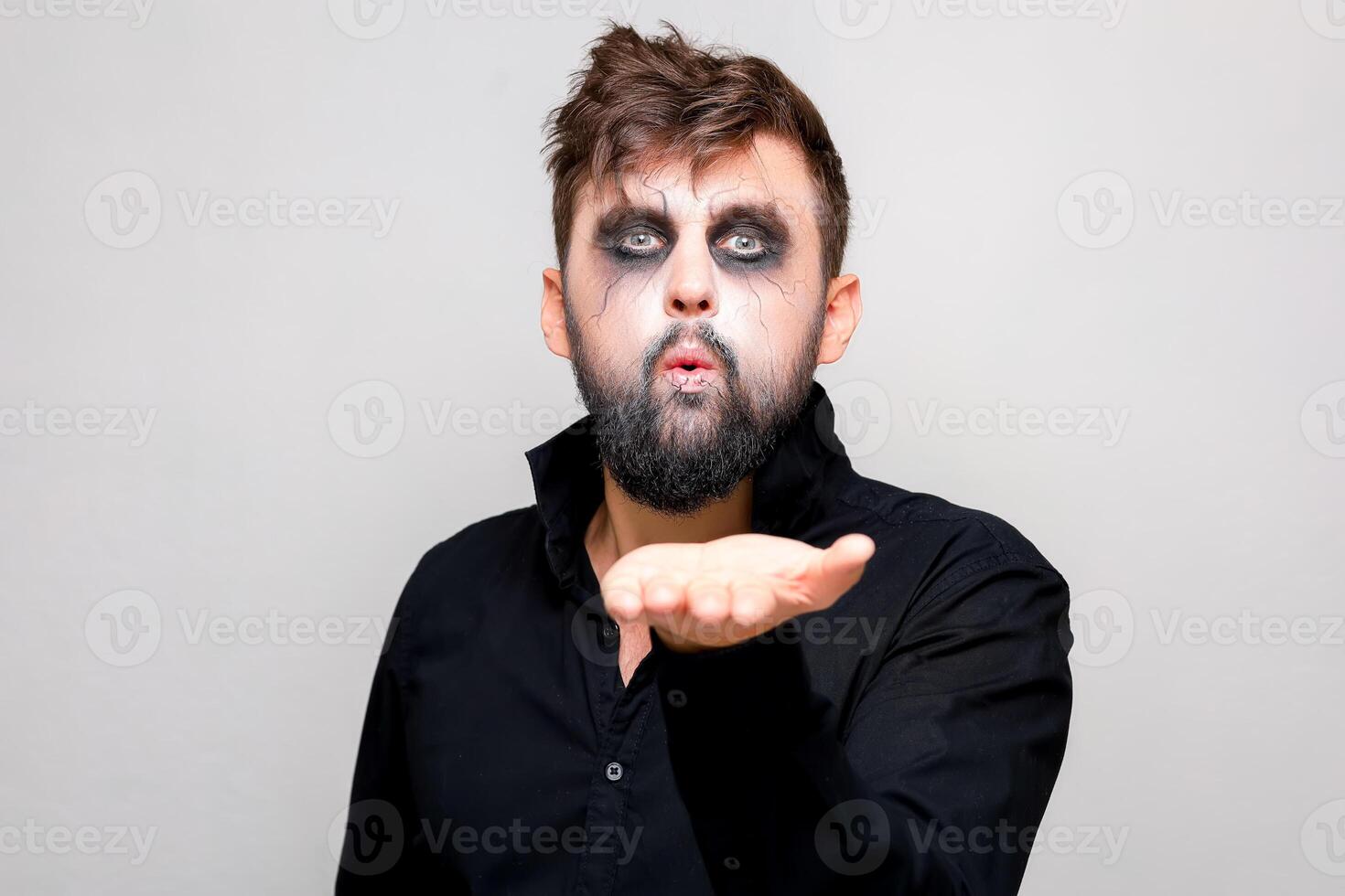 a man with a beard and undead makeup on Halloween holds his hands in front of him photo