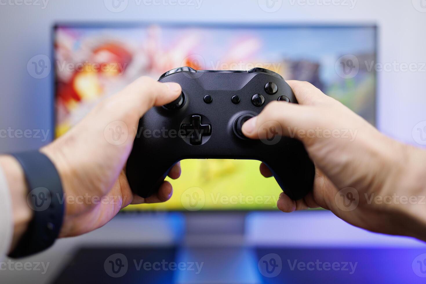 Hands hold a game controller in front of the monitor. game gamepad in hand photo