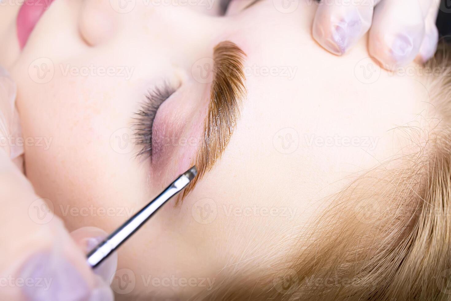 macro photography with applied paint on the hairs of the eyebrows of the model after the procedure of long-term eyebrow styling compositions photo