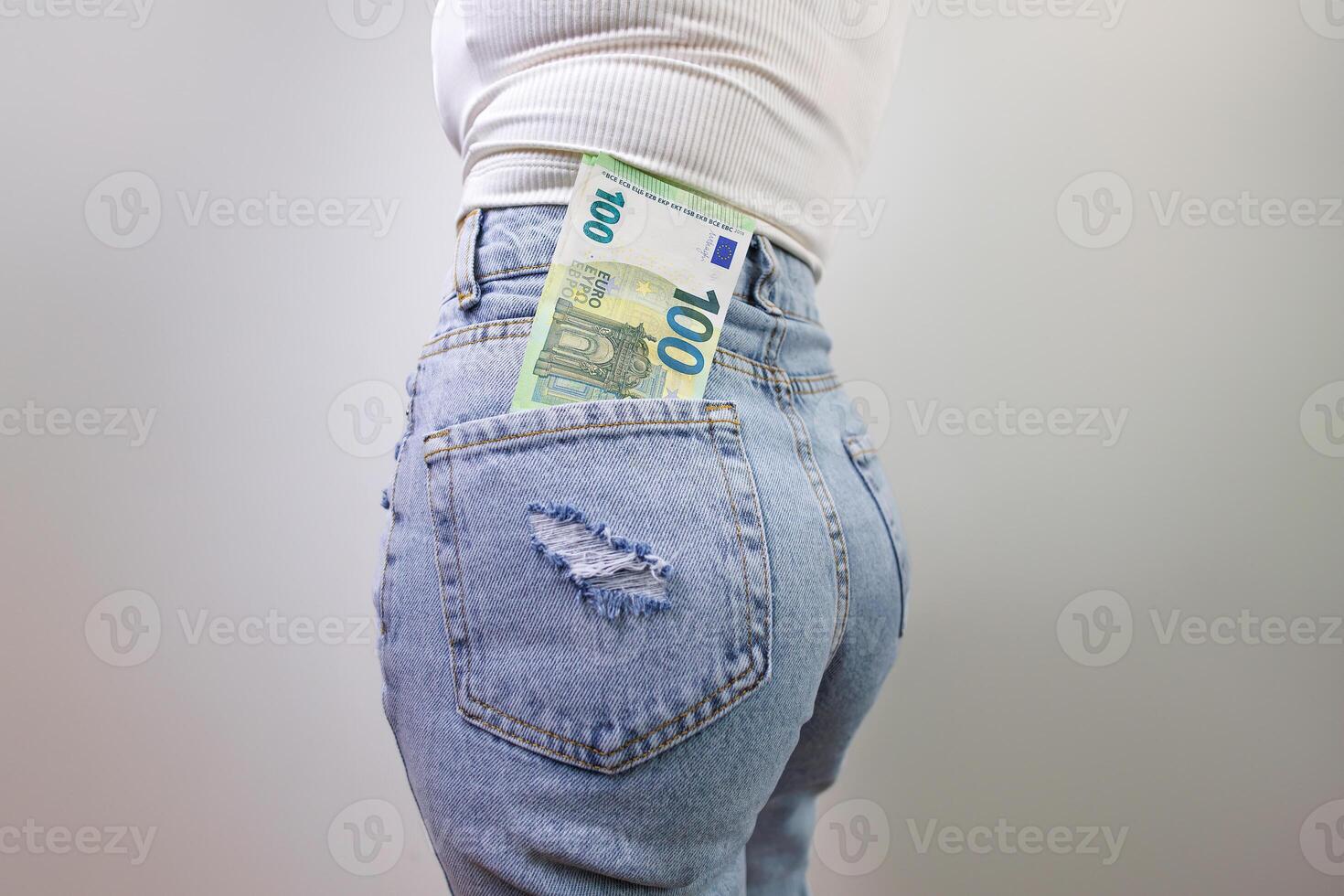 there's a hundred euro bill sticking out of the back pocket of his jeans. A girl in jeans with a euro banknote in her hands. photo