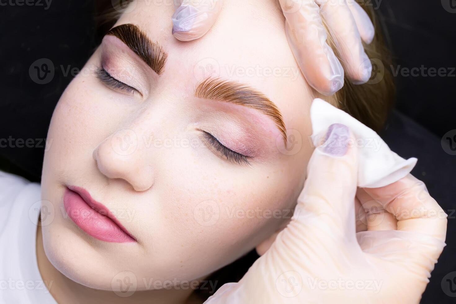 the master removes the remnants of paint from the eyebrows of the model with a cotton sponge photo