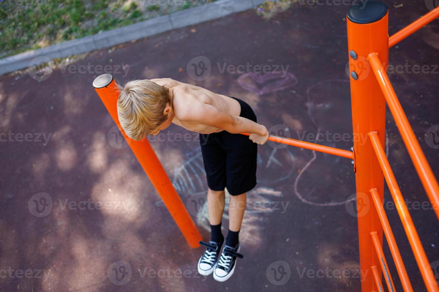 Deportes adolescente en el horizontal bar realiza acrobático ejercicios. calle rutina de ejercicio en un horizontal bar en el colegio parque. foto