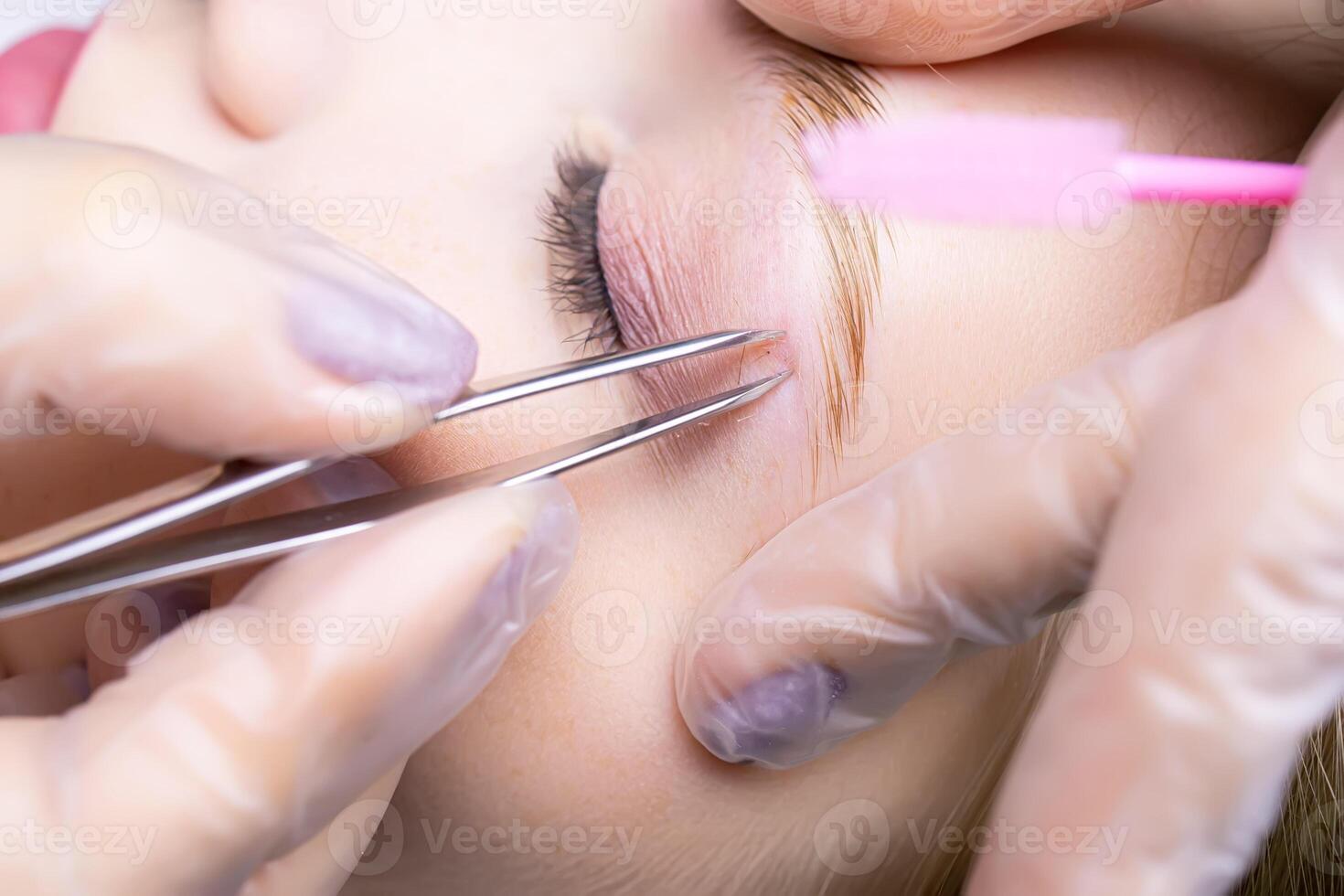 close-up of the eyebrows after the lamination procedure, the master tweezers to pluck the hairs photo