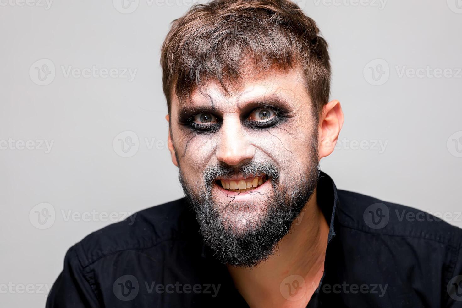 a man with undead-style makeup laughs and shows his teeth photo