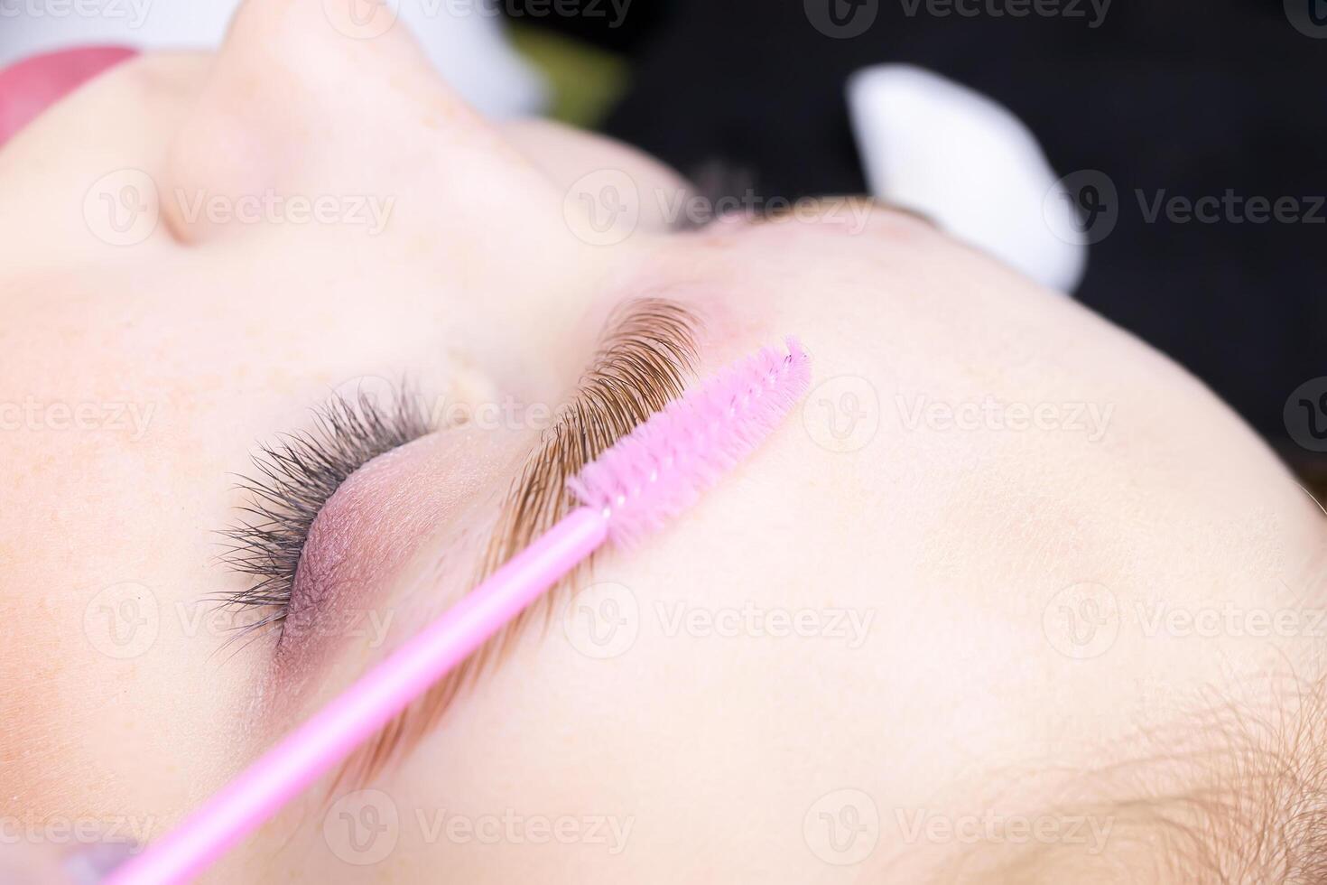 macro photography of the eye, the eyebrow of which is combined with a brush, the hairs are laid after the laminating composition photo