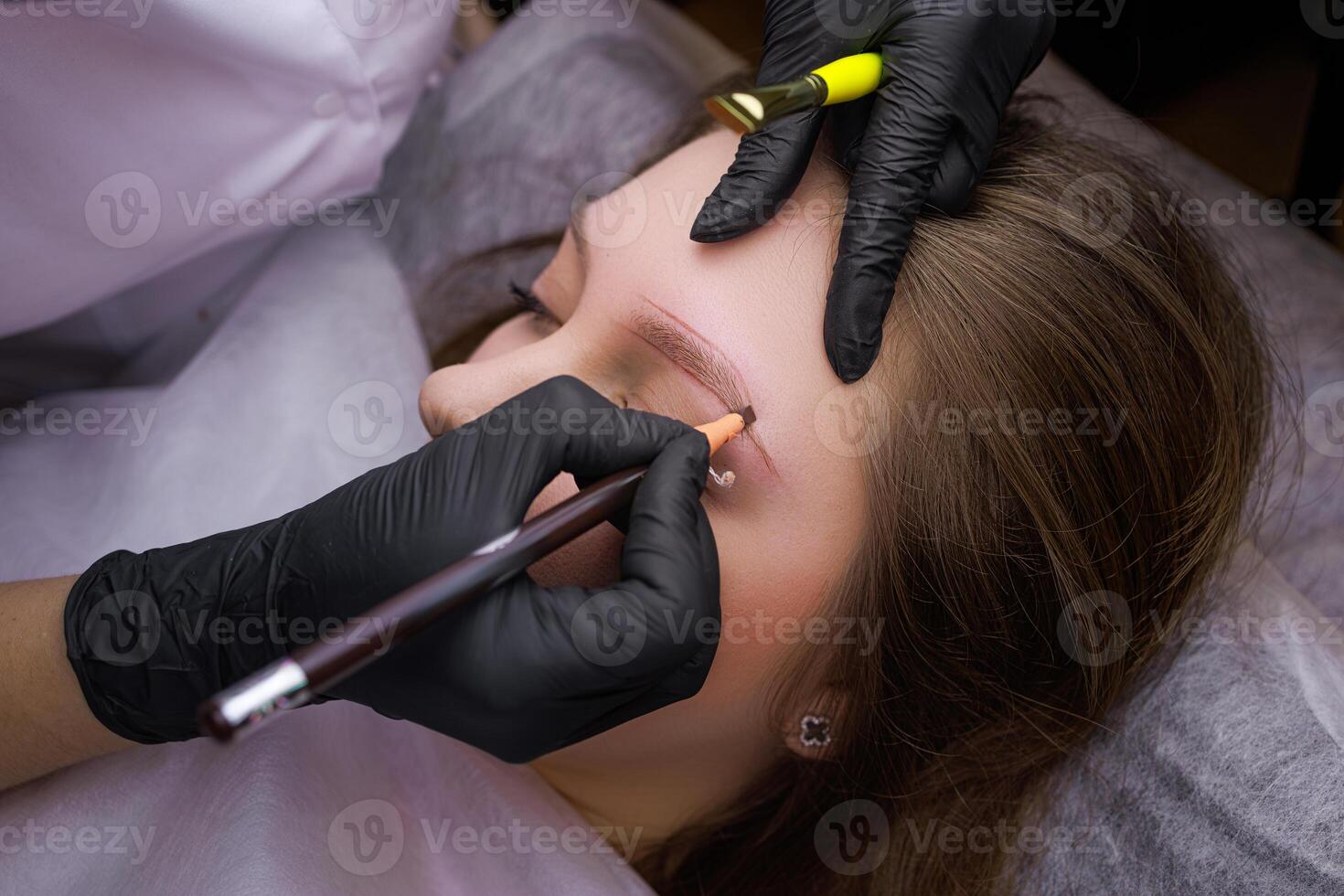 With the help of an eyebrow pencil, the master applies a Marking on the contour before the procedure of permanent makeup. PMU Procedure, Permanent Eyebrow Makeup. photo