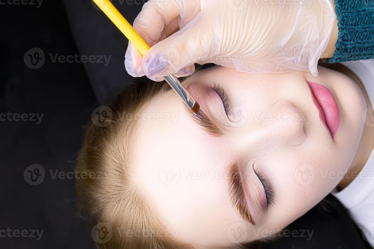 applying hair dye to the eyebrows of the model photo