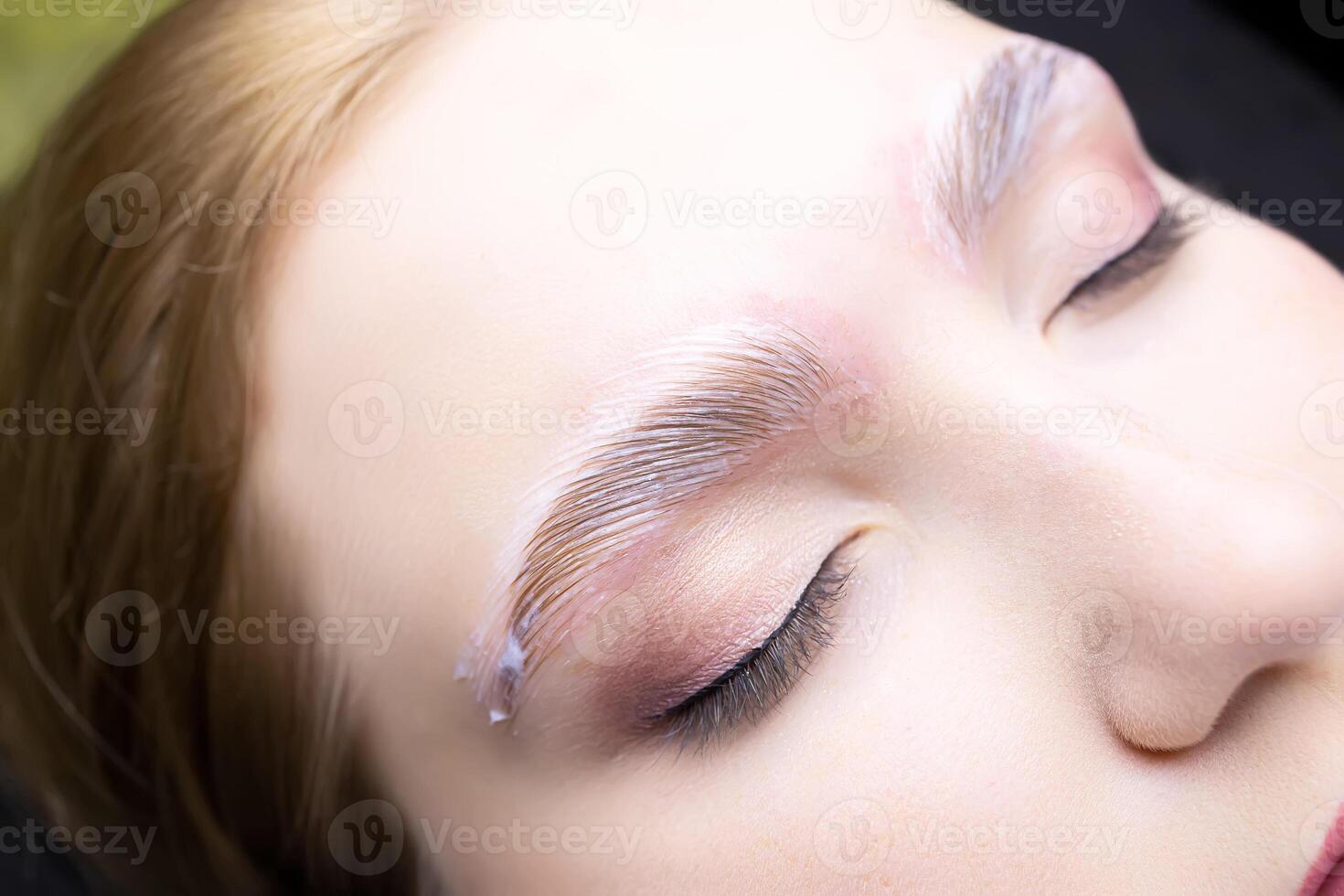 a close-up of the eyebrows of the model on which the procedure of long-term eyebrow styling is performed, laminating compositions are applied to the eyebrows of the models photo