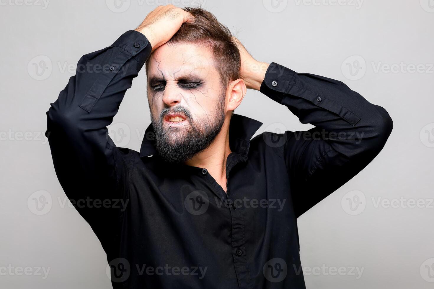 a man with a beard and makeup for Halloween grabbed his hair with his hands photo