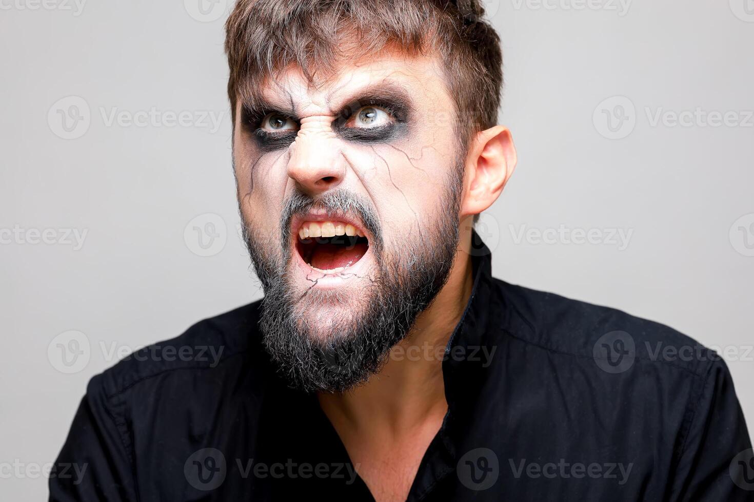 Portrait of a man with a beard and a menacing look with undead-style makeup on All Saints' Day on October 31 photo