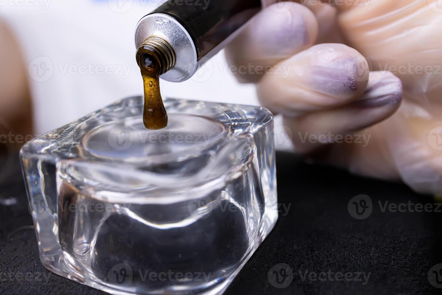 close-up of squeezing eyebrow paint from a tube into a glass cup photo