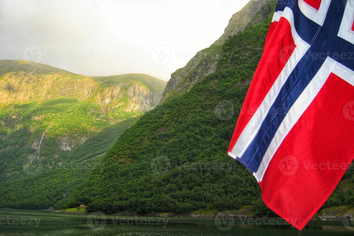 View of Geirangerfjord from the boat with Norwegian flag, Western fjords, Norway. Scandinavian mountains of Sunnylvsfjorden canyon photo