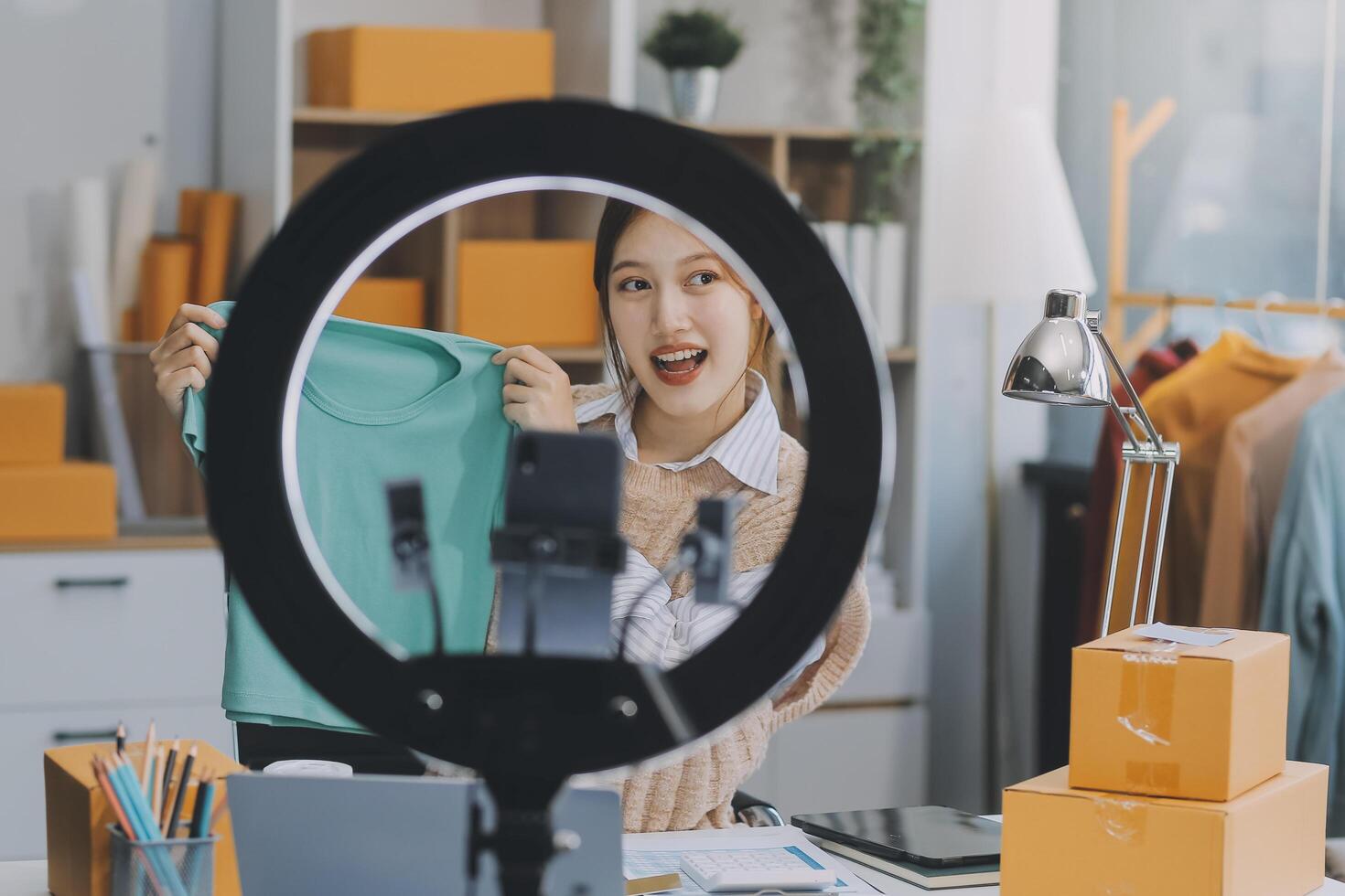 Young woman freelancer working sme business online shopping and packing clothes with cardboard box at home - Business online shipping and delivery concept photo