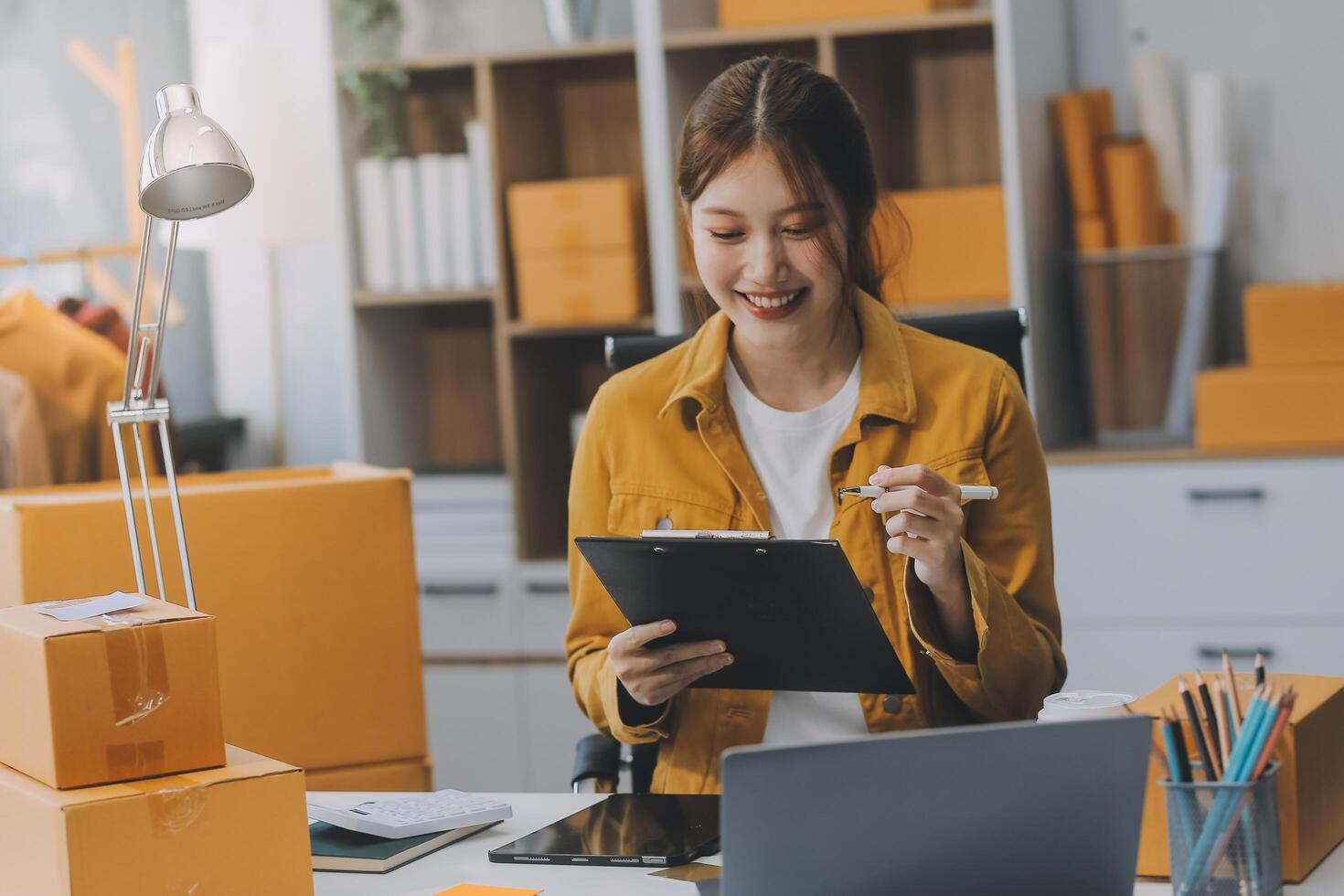 Las pymes asiáticas usan computadoras portátiles para verificar las cajas de envío en línea de pedidos de clientes en casa. Emprendedor de pequeñas empresas pyme freelance. negocio en línea, concepto de trabajo en casa. foto