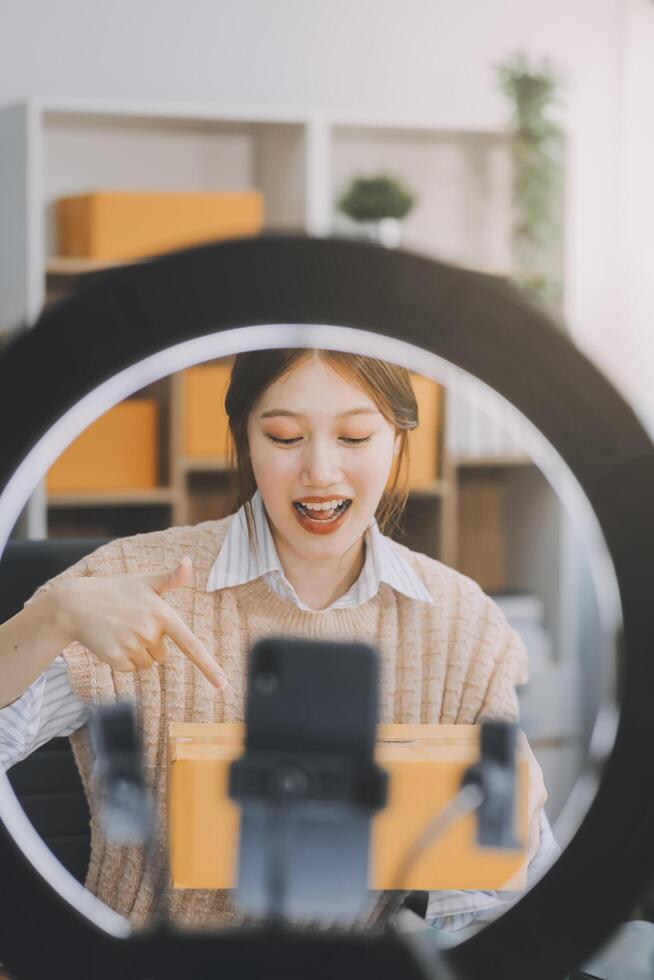 Young woman freelancer working sme business online shopping and packing clothes with cardboard box at home - Business online shipping and delivery concept photo