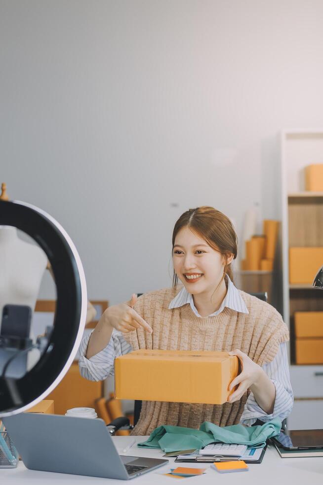 Young woman freelancer working sme business online shopping and packing clothes with cardboard box at home - Business online shipping and delivery concept photo