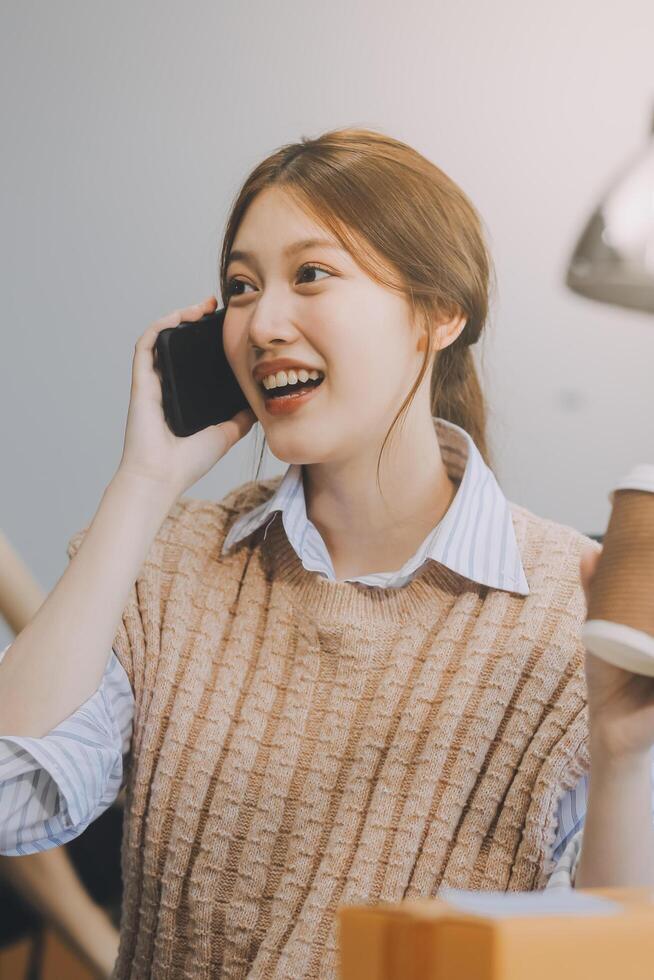 la diseñadora de moda asiática madura trabaja en un estudio creativo, bebe café, contempla y piensa en ideas, imagina una colección de diseño de vestidos y es una empresaria profesional de sastrería boutique. foto