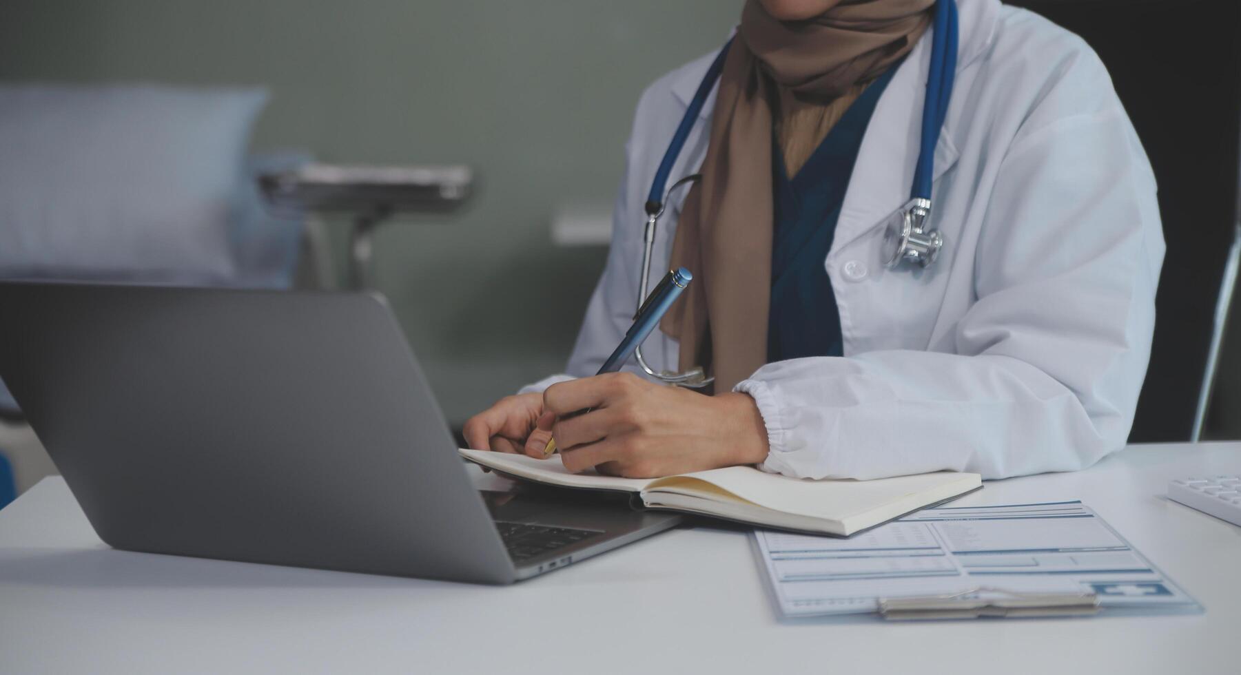 Female doctor sitting at desk and writing a prescription for her patient photo