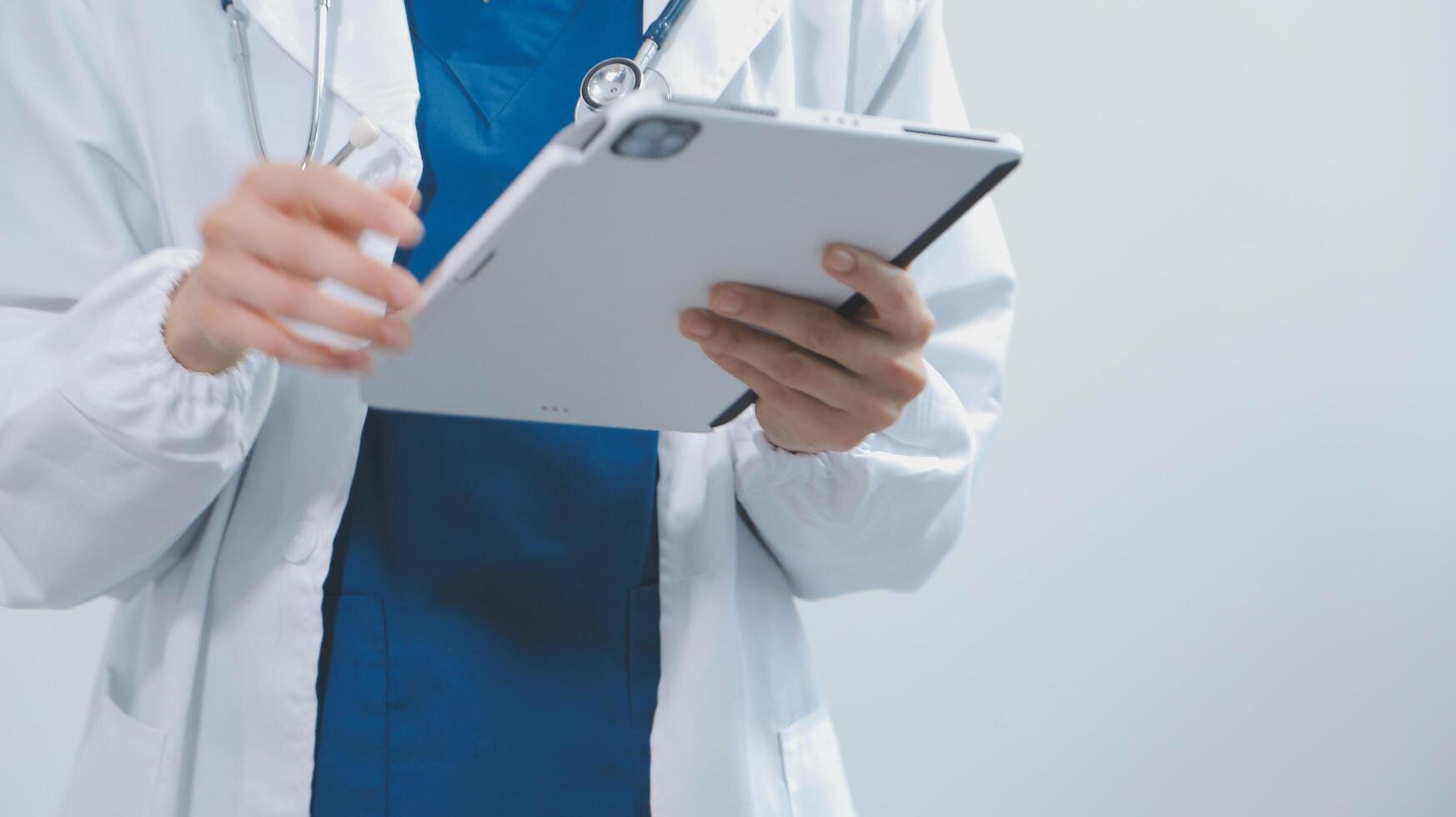 Mature male doctor with tablet pc is giving presentation. Blurred background indoors. photo