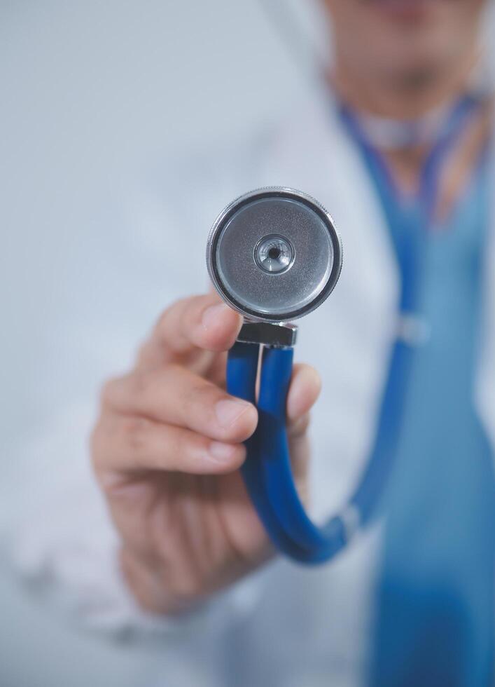 Senior doctor wearing white coat standing holding stethoscope in hands. Older male physician healthcare professional showing medical equipment ready to listen lungs or heart concept. Close up view photo