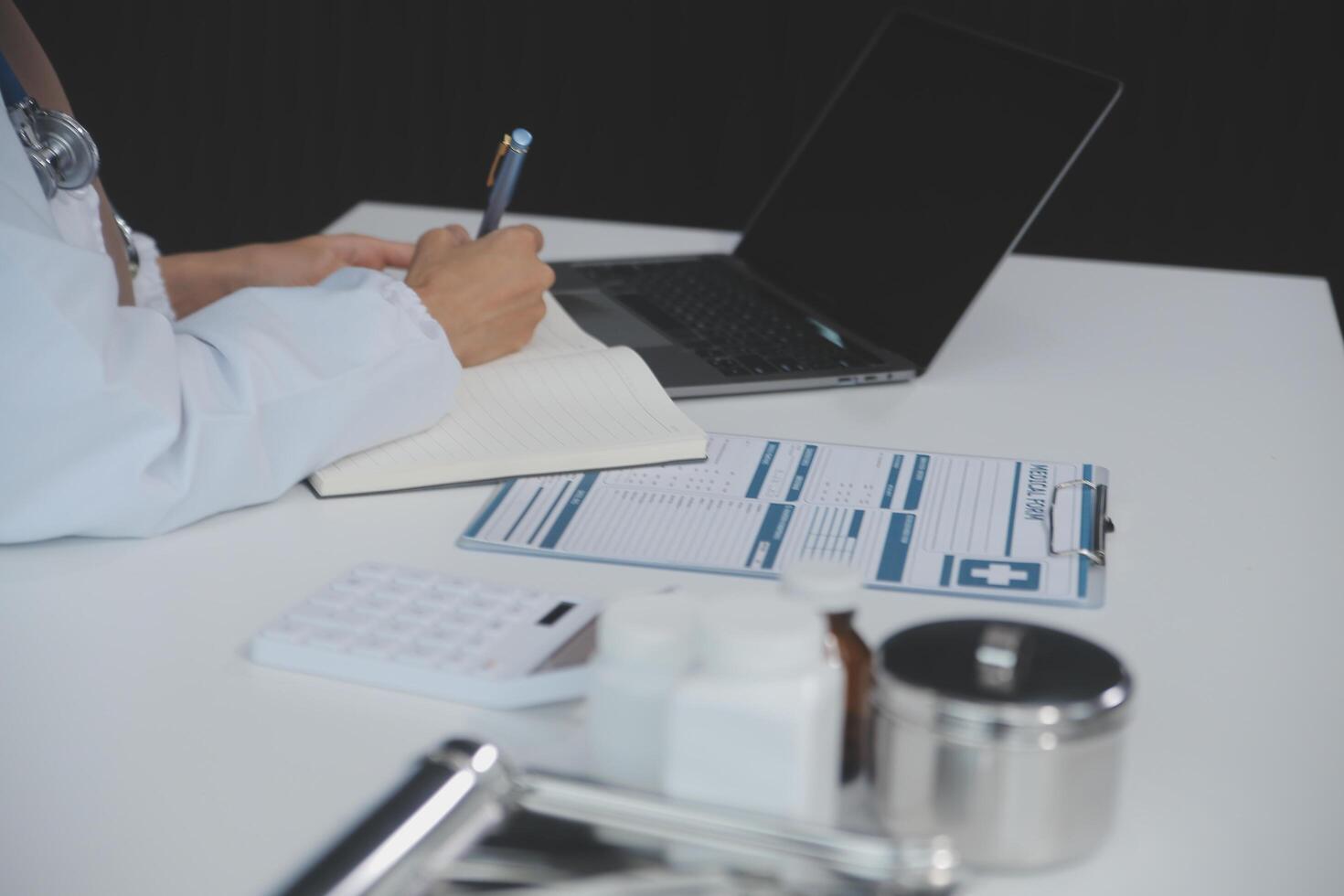 Female doctor sitting at desk and writing a prescription for her patient photo