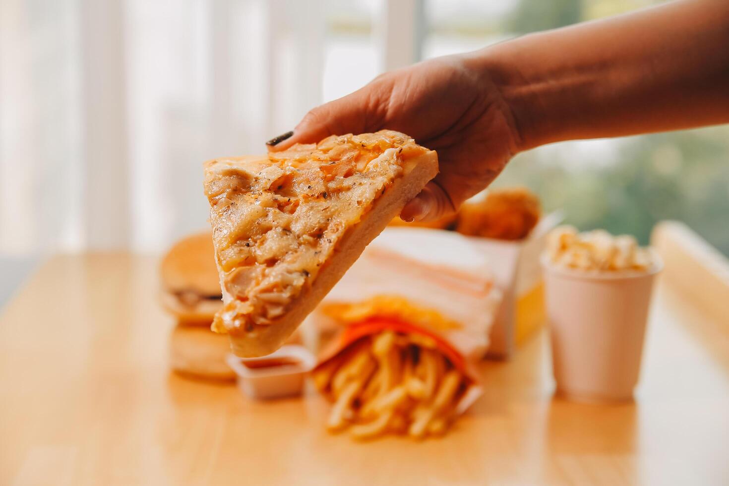 Cropped image of woman holding pizza slice at restaurant photo