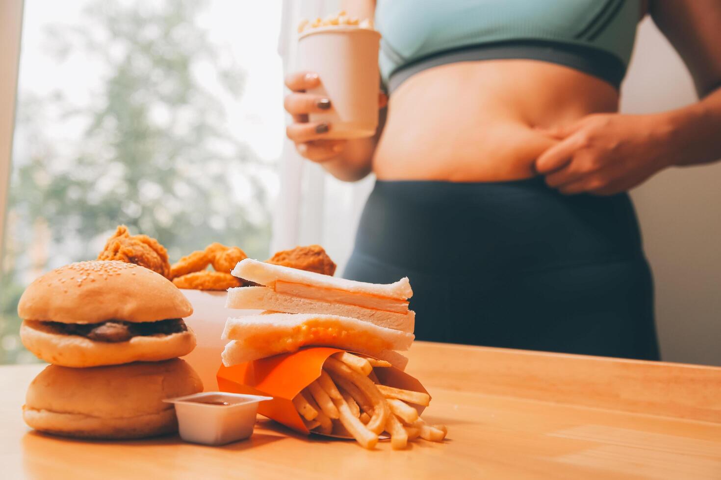 To eat or not. Cheerless plump woman looking at the burger while thinking to eat it or not photo