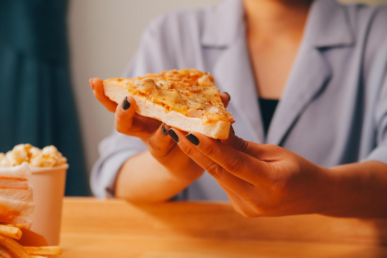 Cropped image of woman holding pizza slice at restaurant photo