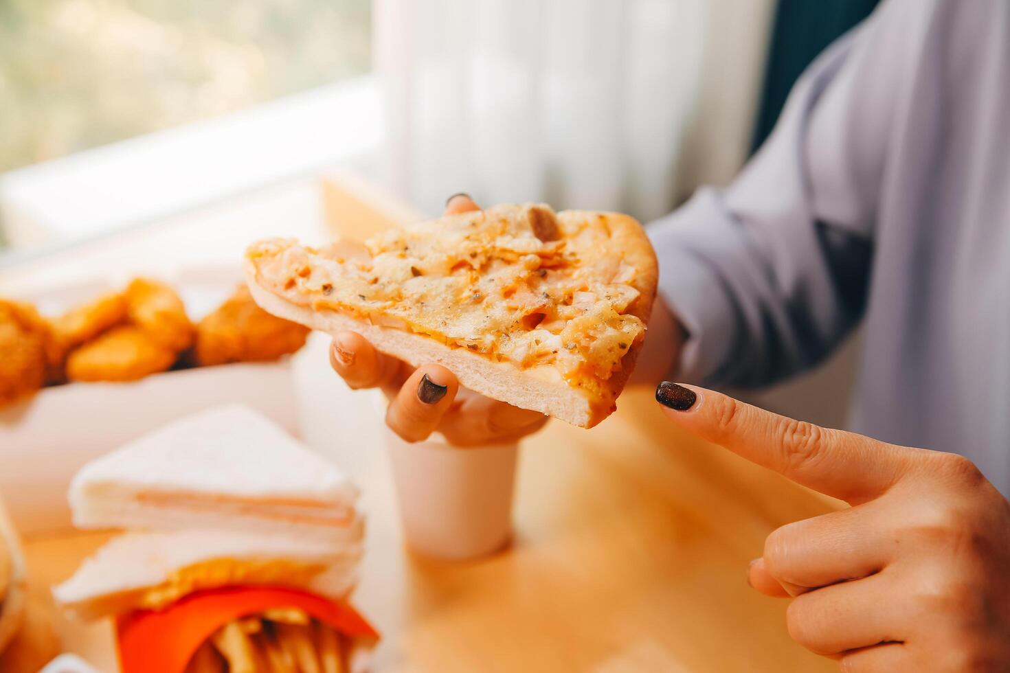 Cropped image of woman holding pizza slice at restaurant photo