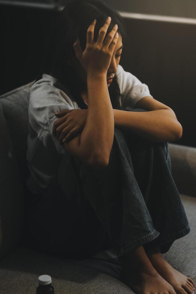 Upset woman frustrated by problem with work or relationships, sitting on couch, embracing knees, covered face in hand, feeling despair and anxiety, loneliness, having psychological trouble photo