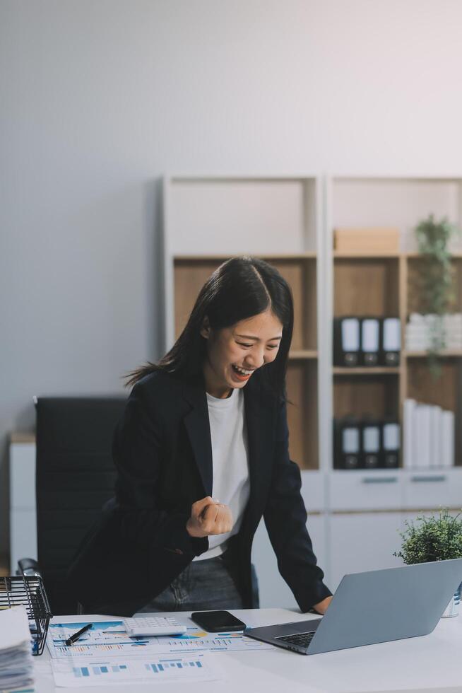 Beautiful Asian girl celebrate with laptop, success happy pose. E-commerce, university education, internet technology, or startup small business concept. Modern office or living room with copy space photo