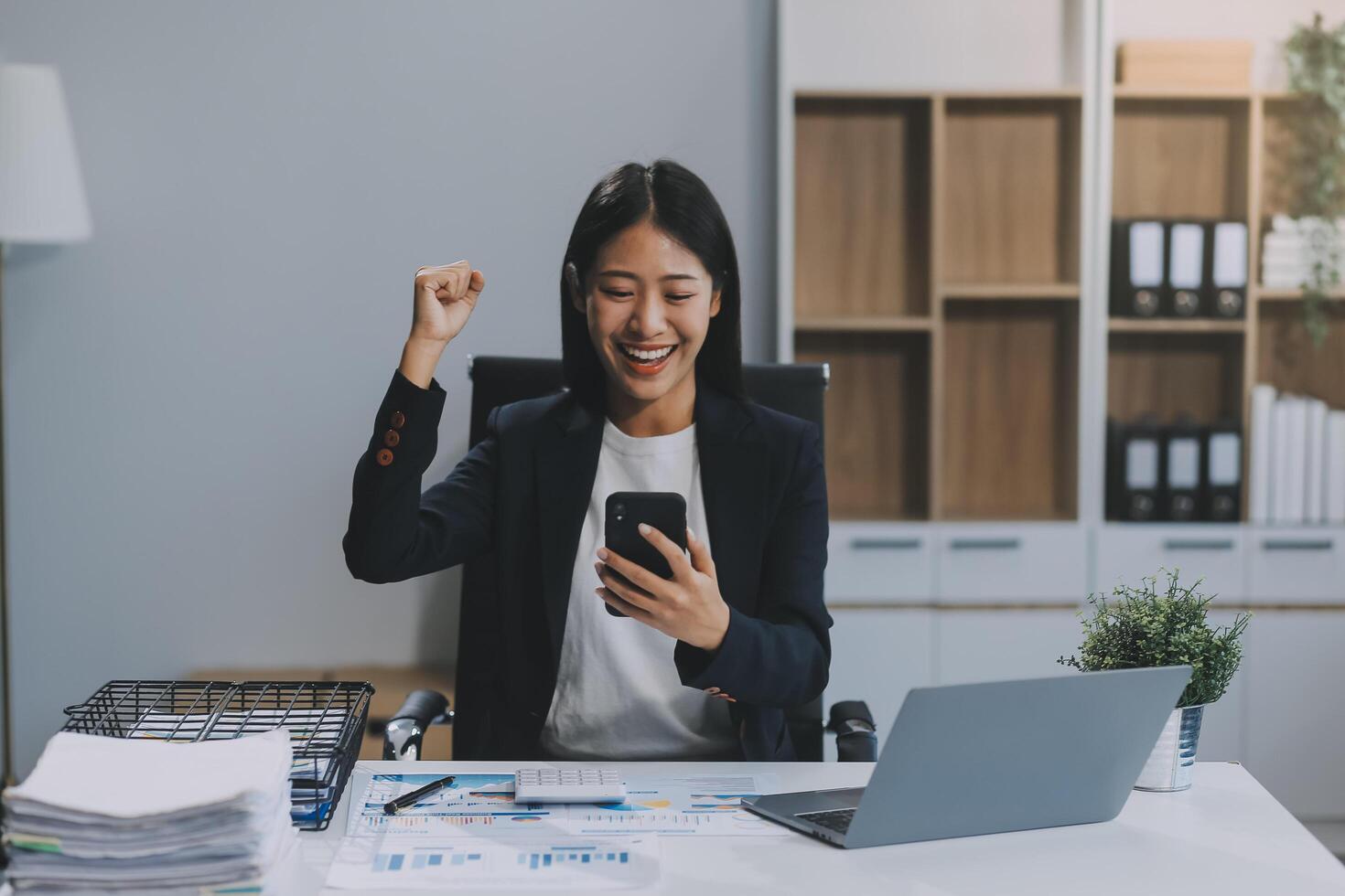 Beautiful Asian girl celebrate with laptop, success happy pose. E-commerce, university education, internet technology, or startup small business concept. Modern office or living room with copy space photo