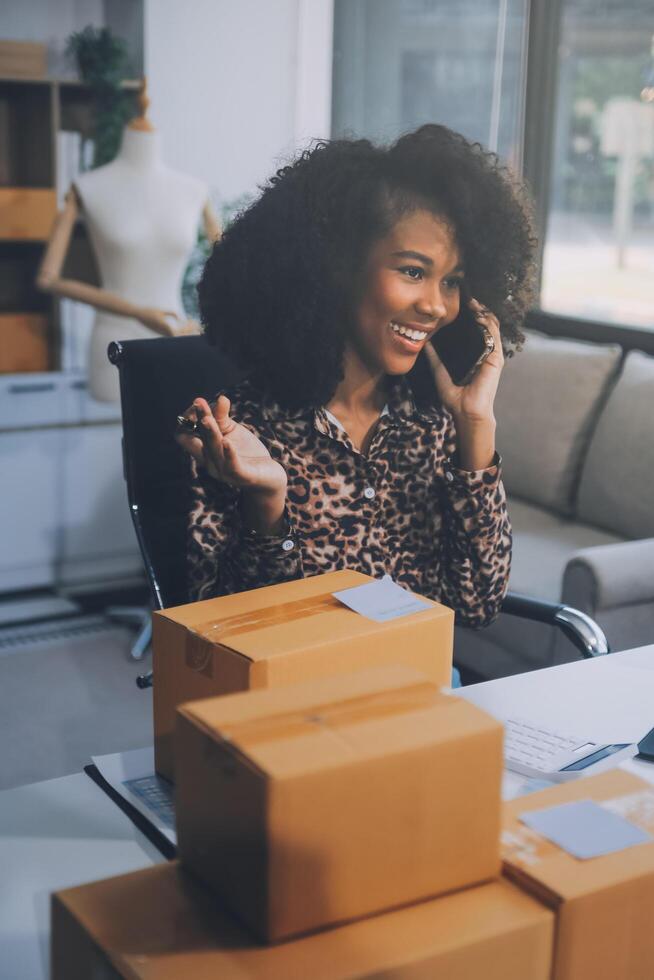 Startup small business entrepreneur or freelance Asian woman using a laptop with box, Young success Asian woman with her hand lift up, online marketing packaging box and delivery, SME concept. photo