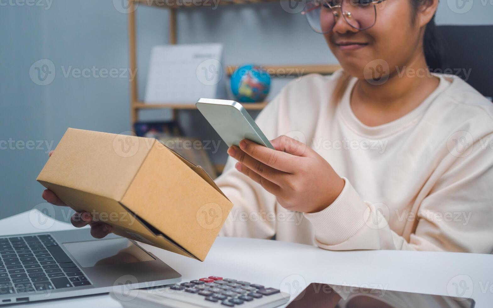 Woman runs an e-commerce business is checking orders from laptop, she owns an online store, she packs and ships through a private transport company. Online selling and online shopping concepts. photo