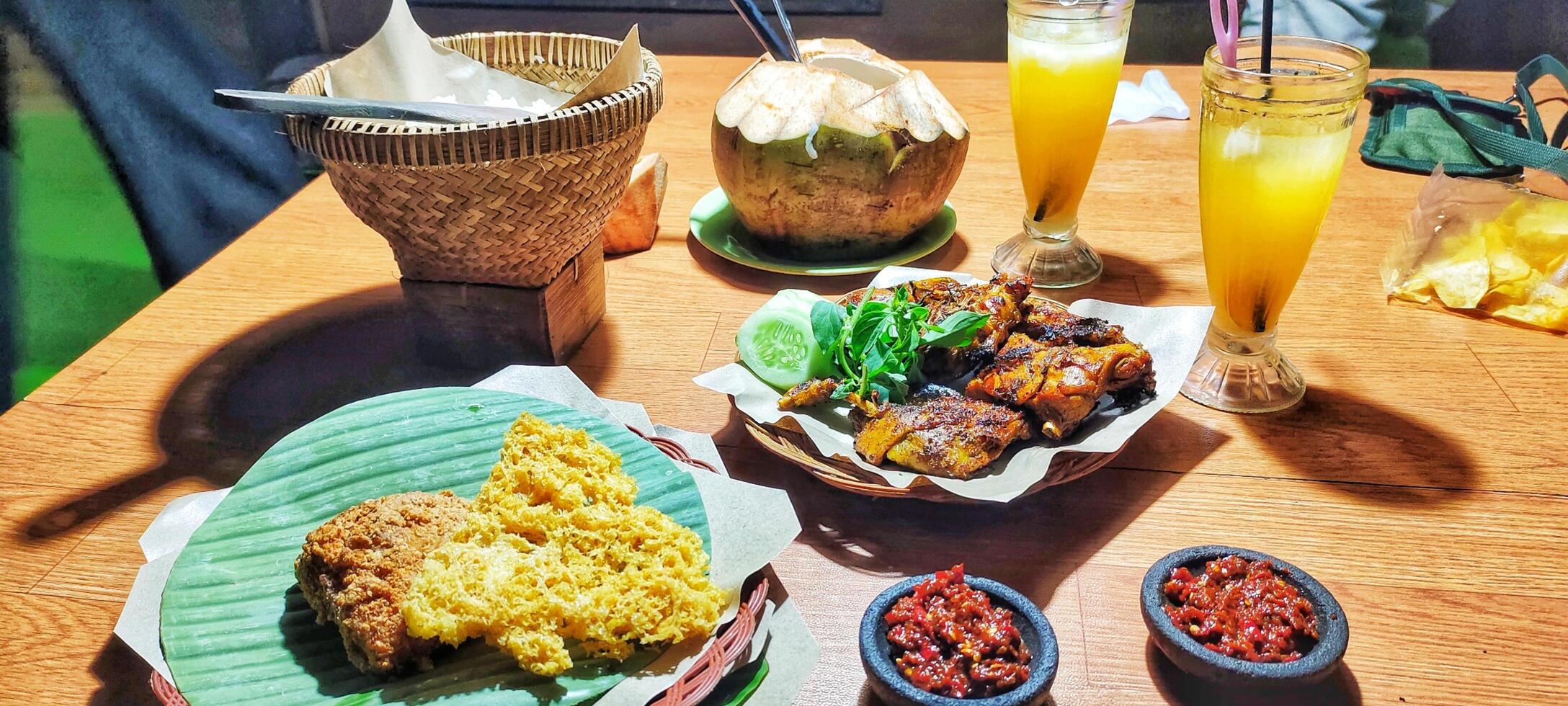 Grilled chicken served with rice, shrimp paste chili sauce, cucumber slices and basil leaves. Original Indonesian grilled chicken recipe. photo