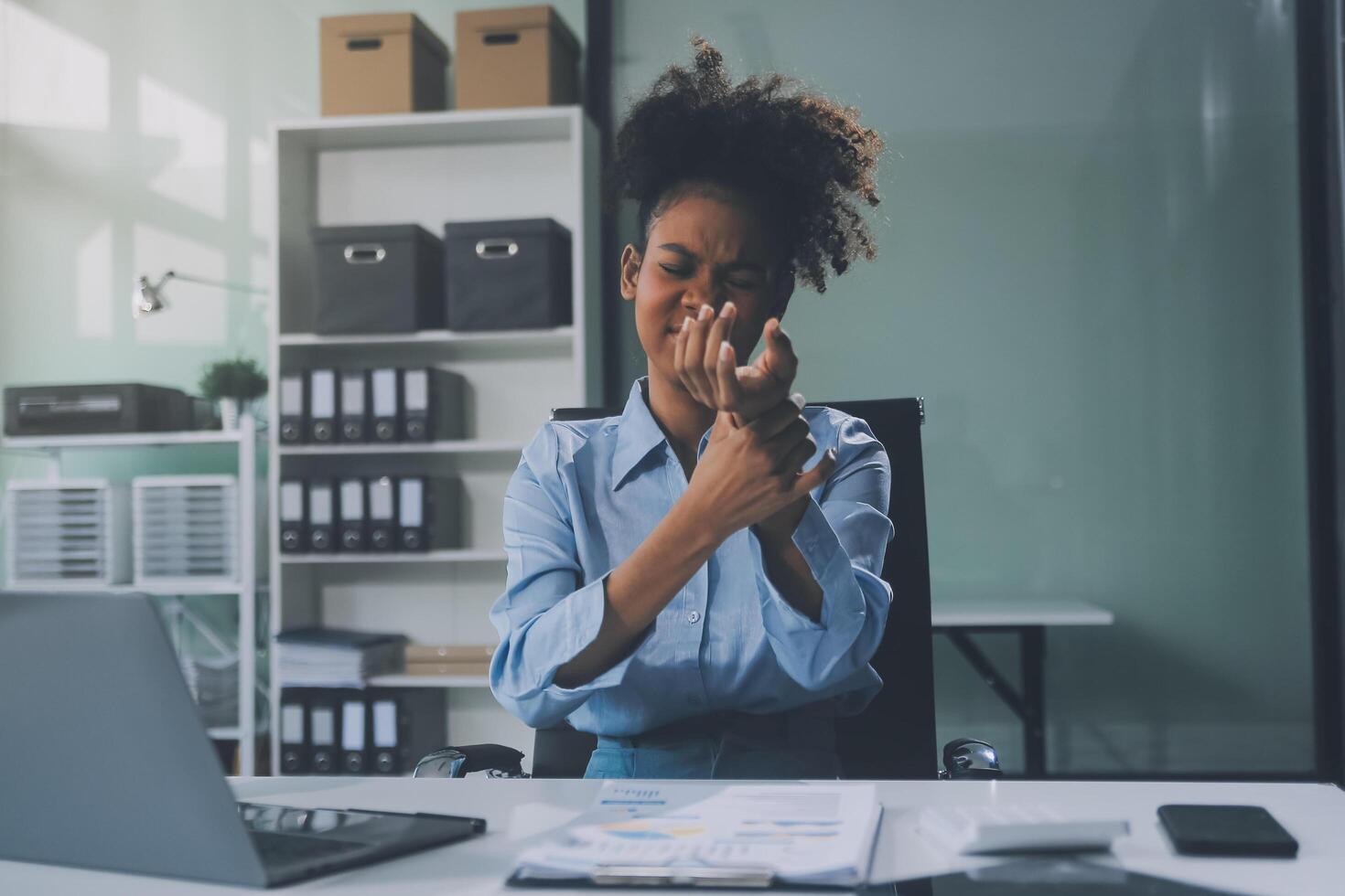 Asian woman working hard in the office having aches and pains in her torso and waist photo