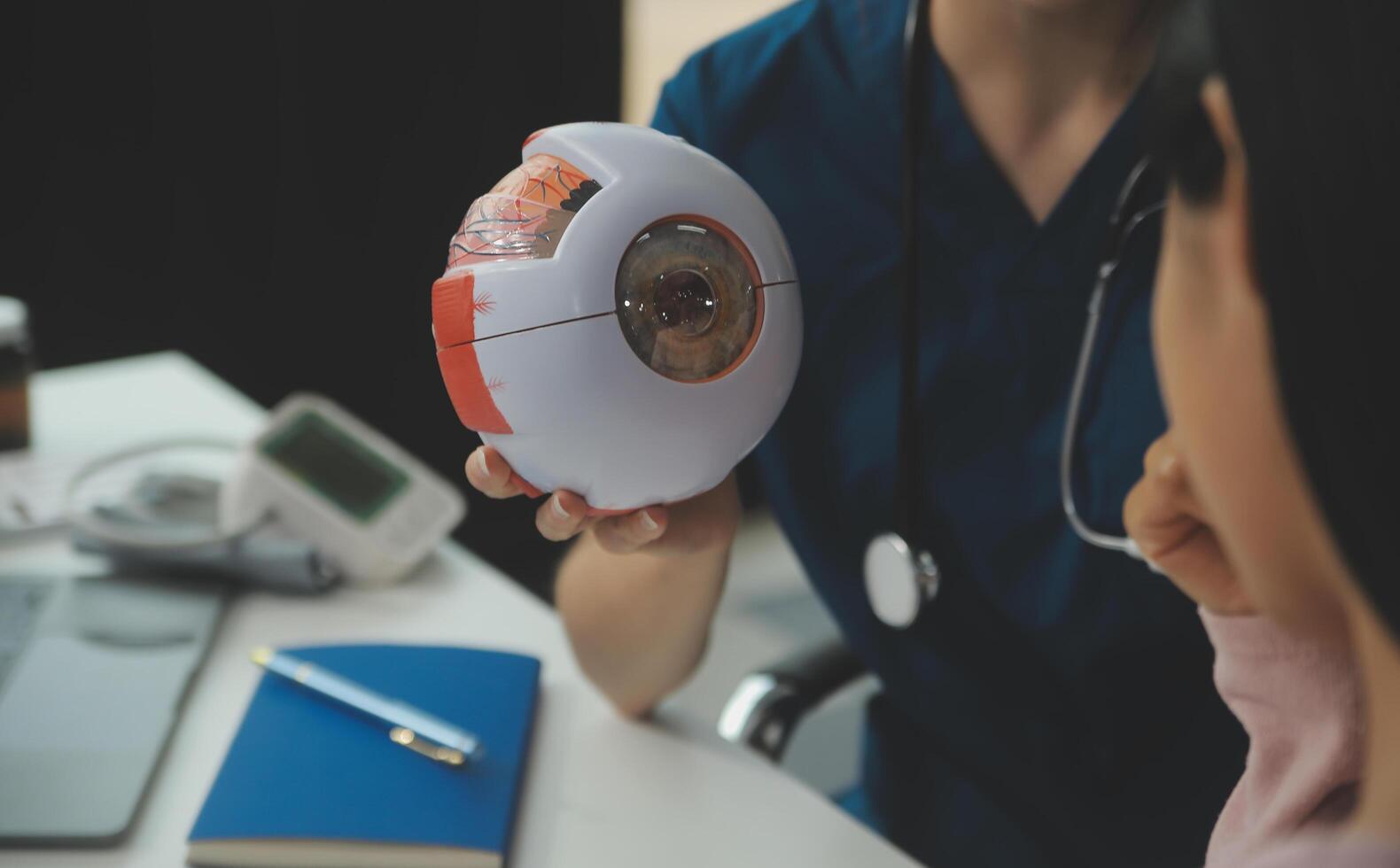 Ophthalmologist doctor in clinic, part of eye model on desk, oculus sample photo