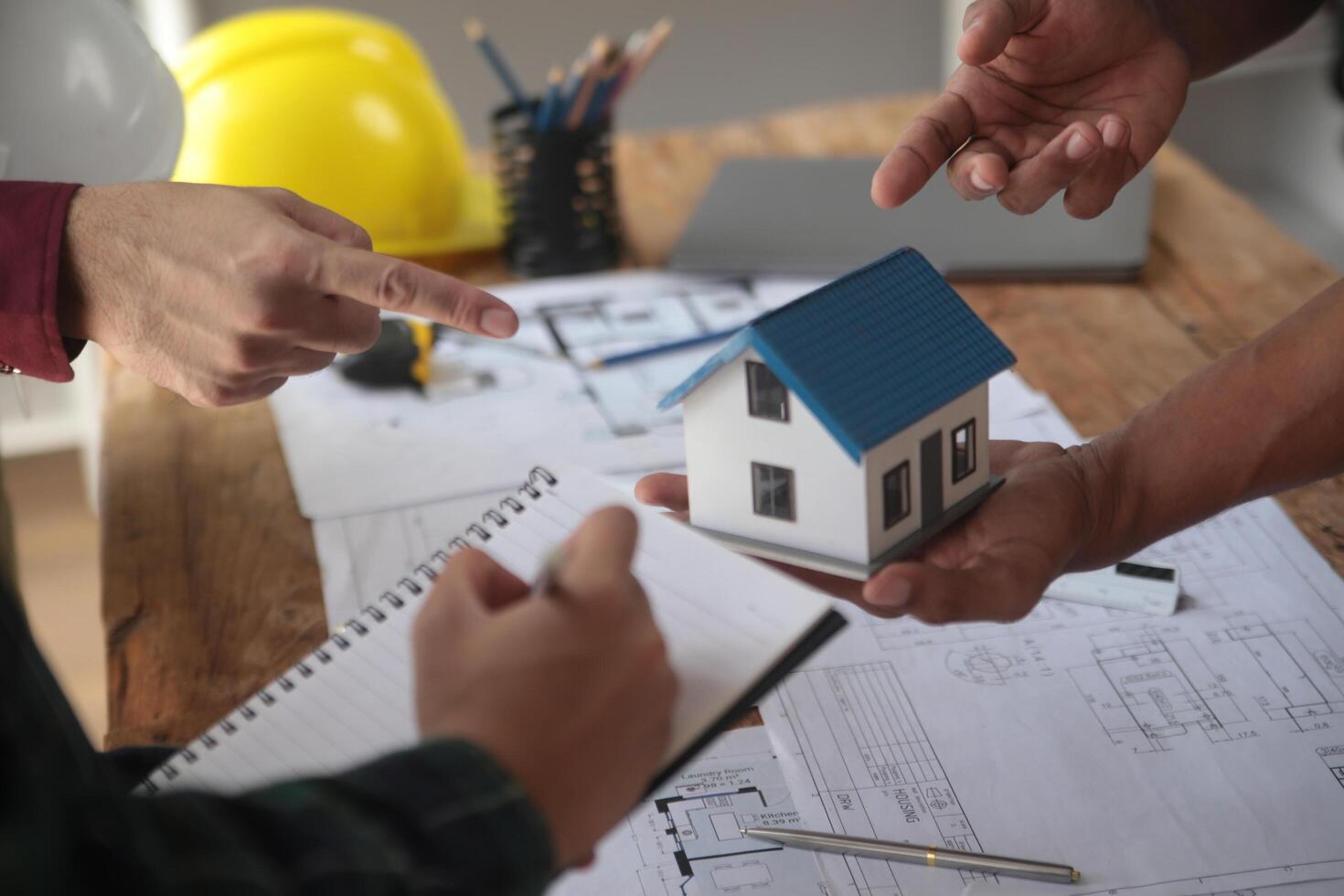 ingenieros son consultante el equipo a diseño un arquitectónico estructura para clientela con planos y edificio modelos a trabajo a oficina. foto