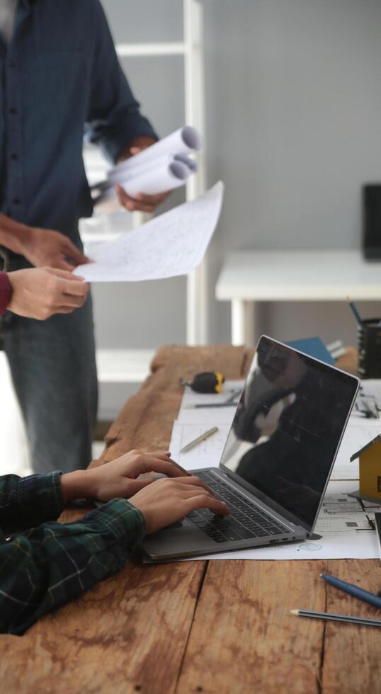 diverso equipo de especialistas utilizar ordenador portátil en construcción sitio. real inmuebles edificio proyecto con ingeniero inversor y empresario comprobación área, trabajando en civil ingeniería, que se discute estrategia plan foto