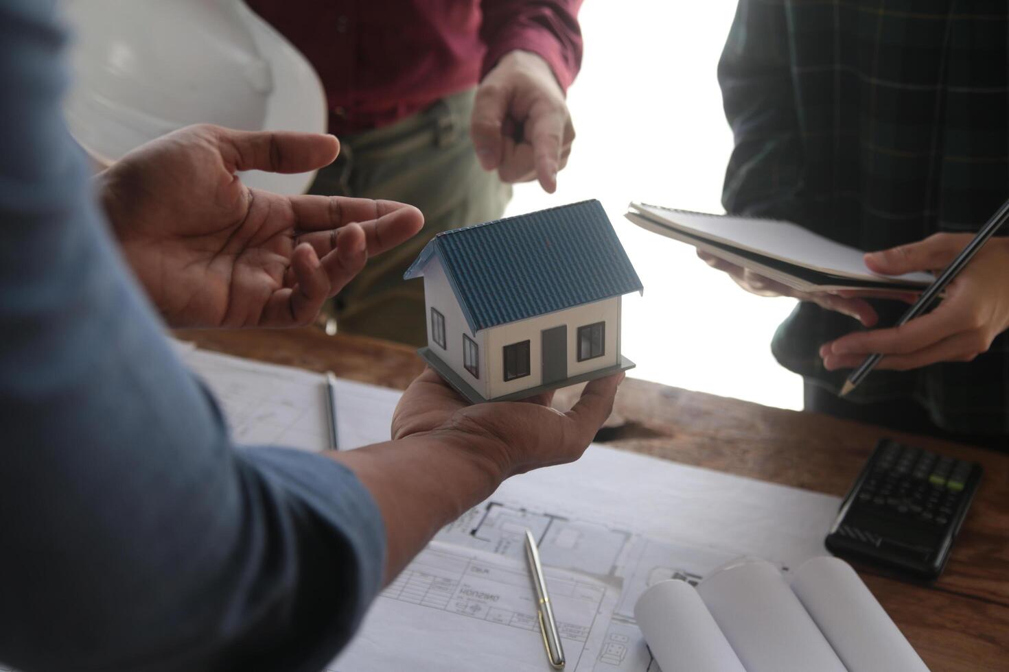 Engineers are consulting the team to design an architectural structure for clients with blueprints and building models to work at office. photo