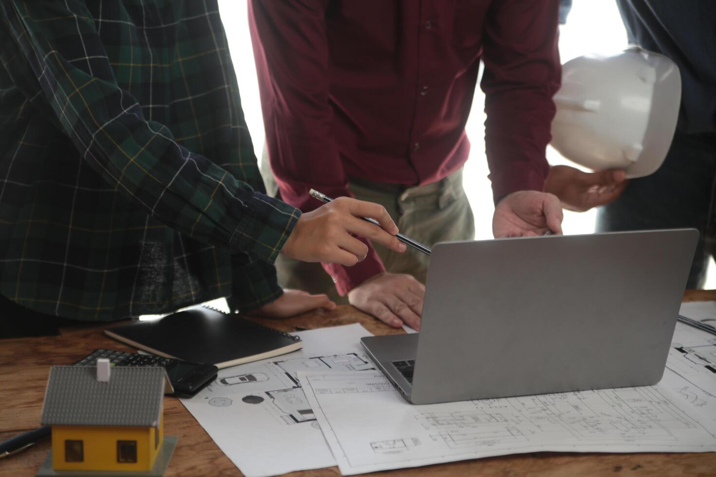 ingenieros son consultante el equipo a diseño un arquitectónico estructura para clientela con planos y edificio modelos a trabajo a oficina. foto